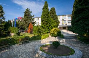 a park with a tree and benches in front of a building at Strandzha Hotel - Free Parking in Golden Sands