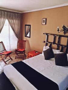 a bedroom with a bed, chair, and lamp at Safari Travelodge in Kuruman