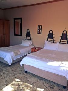 a hotel room with two beds and two lamps at Safari Travelodge in Kuruman