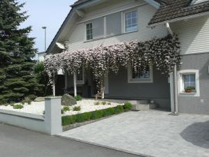 una casa con un árbol floreciente delante de ella en Ferienwohnung Grienwald en Dornbirn