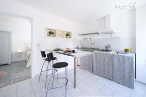 a white kitchen with a counter and stools in it at Villa D Apartments in Marino