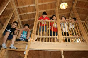 a group of children sitting in a wooden room at Pension Snadun in Ginoza