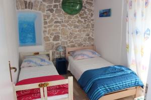 a bedroom with two beds and a stone wall at Mimi in Jadranovo