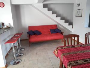 a living room with a red couch and a staircase at Departamento Meliades in El Bolsón