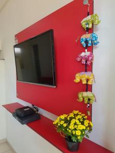 Una pared roja con TV y flores. en Studio Ana Laura, en São Paulo