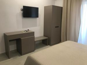 a bedroom with a bed and a desk and a tv at Golden View Residence in Dhërmi