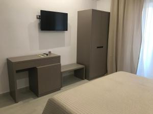 ein Schlafzimmer mit einem Bett, einem Schreibtisch und einem Fernseher in der Unterkunft Golden View Residence in Dhërmi