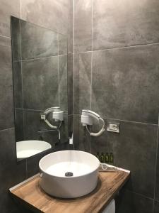 ein Badezimmer mit einem weißen Waschbecken und einem Spiegel in der Unterkunft Golden View Residence in Dhërmi + 12 Fotos
