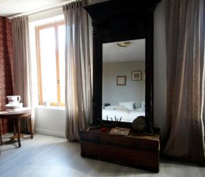 einen Spiegel in einem Zimmer mit einem Bett und einem Fenster in der Unterkunft Arara in Montfaucon-dʼArgonne