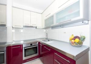 a kitchen with red cabinets and a bowl of fruit at Apartment Dormir Split in Split