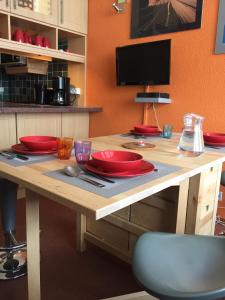 ティーニュにあるStudio au pied des pistes et funiculaireの木製テーブル(赤皿、調理器具付)