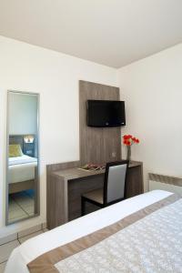 1 dormitorio con 1 cama y escritorio con TV en Séjours & Affaires Clermont Ferrand Park République, en Clermont-Ferrand