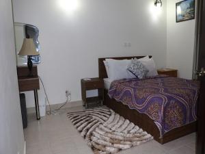 a bedroom with a bed and a lamp and a rug at Jaria Apartments in Accra