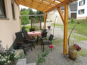 eine Terrasse mit einem Tisch, Stühlen und einem Sonnenschirm in der Unterkunft Vronis Ferienwohnungen in Mühlingen