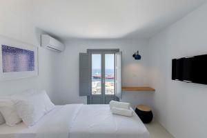 a white bedroom with a bed and a window at Sealine Villas in Tourlos +43 photos