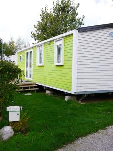 a green and white tiny house in a yard at Camping Les Vertes Feuilles in Quend