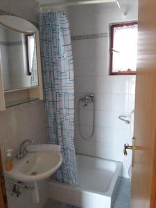 a bathroom with a sink and a tub and a shower curtain at Apartments Stipanovic in Biograd na Moru