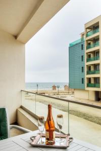 a bottle of wine and two glasses on a table with the beach at Apartament La Plaja in Mamaia Nord
