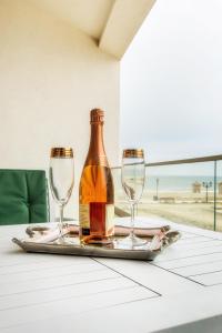 a bottle of wine and two wine glasses on a table at Apartament La Plaja in Mamaia Nord