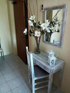 a table with a vase of flowers and a mirror at Foteini Rooms in Skala Sotiros