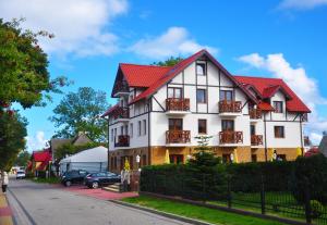 a white house with a red roof on a street at Klif Spa in Jarosławiec