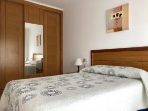 1 dormitorio con 1 cama con edredón blanco en Apartamentos Lúa, en Portonovo