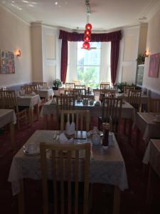 een restaurant met tafels en stoelen en een groot raam bij Adelphi Guest House in Douglas