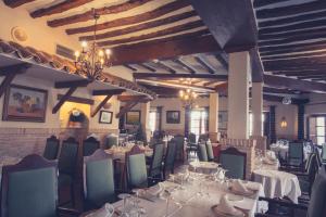 a dining room with tables and chairs and a chandelier at Hotel Mesón de Don Quijote in Mota del Cuervo