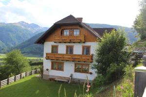 ein Haus mit einem Holzdach auf einem grünen Feld in der Unterkunft Ferienwohnung Bliem in Sankt Michael im Lungau