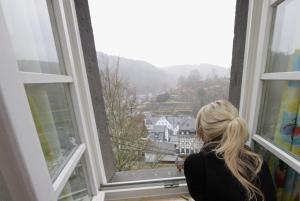 Una mujer mirando por una ventana a una ciudad en Ferienwohnungen Burg Monschau, en Monschau