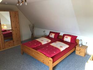 Schlafzimmer mit einem großen Holzbett mit roter Bettwäsche in der Unterkunft Ferienhaus Kira in Boltenhagen