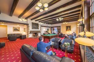 a group of people sitting in a living room with a pool table at Hotel Luisa in Františkovy Lázně