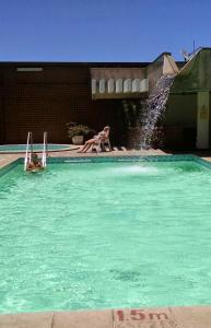 two people in a swimming pool with a fountain at Flat Pasárgada 712, Free Bikes, pé na praia in Vila Velha