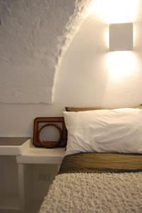 una camera da letto con un letto con un cuscino bianco e una lampada di I 7 Archi Guest House a Ostuni