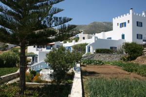 a group of white buildings with a tree in the foreground at Flora's Apartments in Apollon