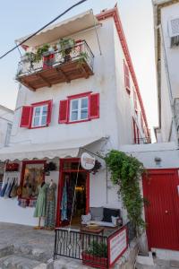 a white building with red windows and a store at Bahia in Hydra