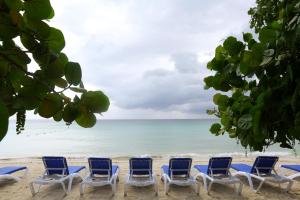 a row of chairs on a beach with the ocean at Merrils Beach Resort II in Negril