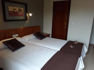 2 camas en una habitación de hotel con faldas en Hostal Rural El Campito en San Martín del Castañar