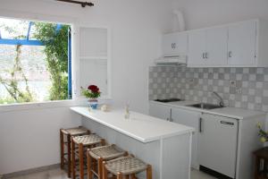 a kitchen with white cabinets and a counter with stools at Flora's Apartments in Apollon