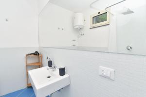 een badkamer met een witte wastafel en blauwe tegels bij Casa Partenope in Ischia