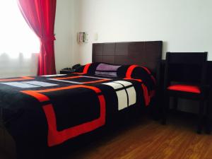 a bed with a black and red blanket and a chair at Hotel San José Ipiales in Ipiales