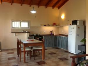 a kitchen with a table and a white refrigerator at El Pinar - Hospedaje Serrano in Tanti
