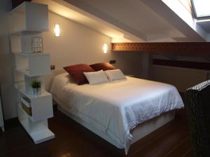 ログローニョにあるAtico Portales, Diseño en el casco antiguo de Logroñoのベッドルーム1室(白いシーツと赤い枕のベッド1台付)