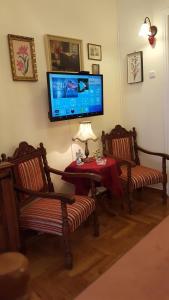 a living room with two chairs and a tv on the wall at KOKONI APARTMENT De'Luxe CENTRAL ATHENS in Athens