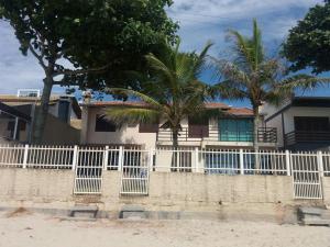 een wit hek voor een huis met palmbomen bij casa na praia in Porto Belo