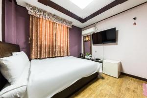 a bedroom with a large white bed and a tv at Keumkang Motel in Seoul +24 photos