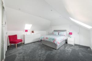 a white bedroom with a bed and a red chair at Monard Villa in Barvas