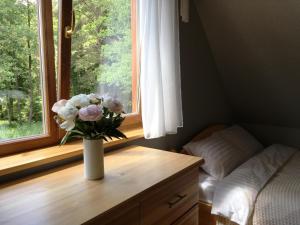 un jarrón de flores sentado en una mesa de madera frente a una ventana en Dīķmalas, en Roja