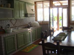 uma cozinha com armários verdes e uma mesa de madeira em L'Oasi di Ambra Dependance em Ardea