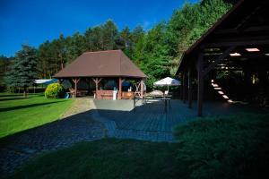 un gazebo con tetto marrone in un parco di Leśniczówka "Przyłęsko" a Rybakowo